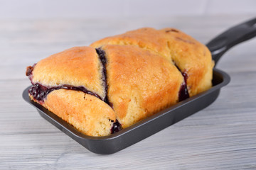 butter blueberry cake in metal black pan on wooden gray background