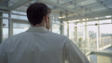 Biotech scientist or doctor in a hospital or lab stands and looks at the horizon