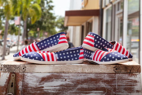 Patriotic American flag shoes are on display in front of a small-town store sidewalk. An American flag design shoes nicely displayed on the 4th of July sale.