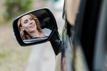 cheerful blonde and attractive woman smiling in car window