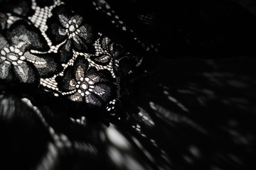 Abstract background of shadows black floral laces on white table. Light going through black lace....
