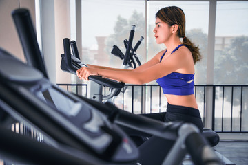 woman asian biking in gym, exercising legs doing workout cycling bikes