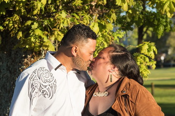 Portrait of an attractive Maori couple kissing taken outdoors