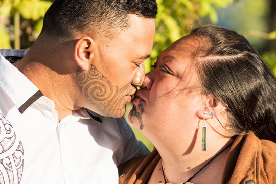 Portrait of an attractive Maori couple kissing taken outdoors