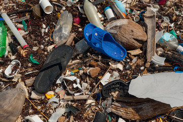Plastic footwear and other garbage on beach, pollution