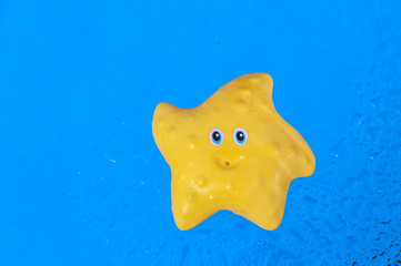Yellow toy starfish on blue surface background