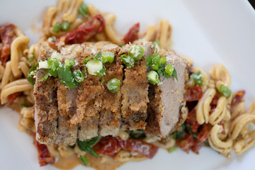 Crusted pork and green onions on a bed of pasta