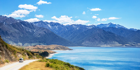 Travel van car driving on road near lake in mountains