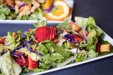 Colorful Strawberry and Orange Salads on a dark background