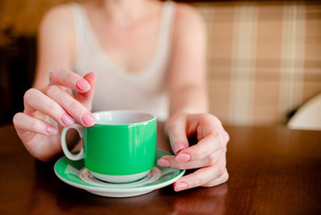 Female hands hold hot green  coffee cup beverage, drinks cappuccino. Horizontal several objects copyspace