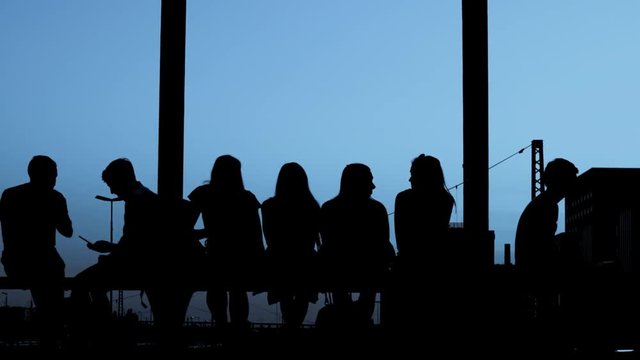 Silhouettes - Group of people is sitting together at evening light - slow motion
