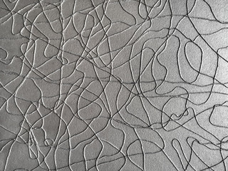 Modern art background from silver rope on gray paper. Abstract backdrop, closeup.