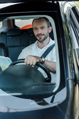 selective focus of handsome man driving car and holding map