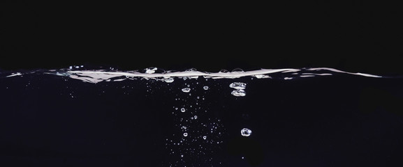 Water bubbles isolated on black background, close up view. Rippling liquid surface, an abstract...