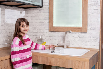 girl picks up a glass of water in the kitchen