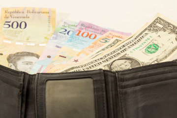 Black leather wallet with Venezuelan money bolivars and US dollar currency.