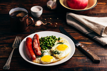 Breakfast with fried eggs, sausages and green peas