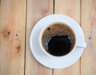 A Cup of hot coffee and coffee beans on wood table. 