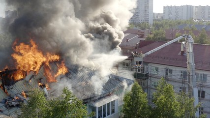 Fototapeta na wymiar Burning roof of a residential high-rise building, clouds of smoke from the fire. firefighters extinguish the fire. top view