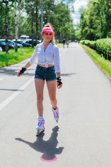 Portrait of an emotional girl in a pink cap visor and protective gloves for rollerblades and...