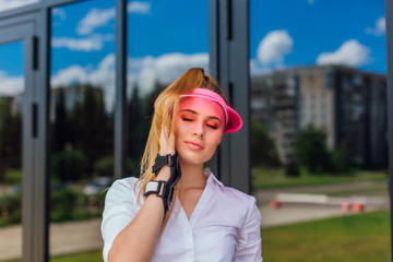 Portrait of an emotional girl in a pink cap visor and protective gloves for rollerblades and skateboarding.