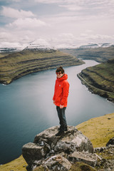 Happy traveler in red jacked on the top of mountain Faroe