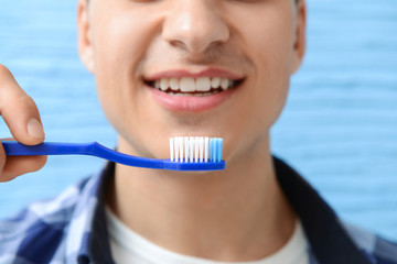 Handsome man with toothbrush on color background, closeup