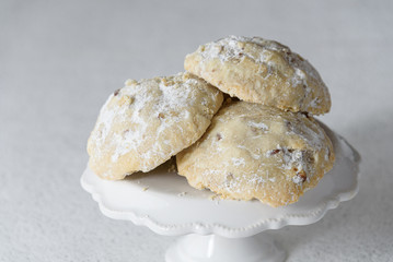 Stack of Russian Tea Cake cookies on a white cake plate on a white background with silver sparkles