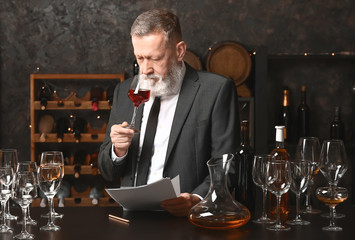 Mature sommelier working in wine cellar