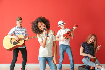 Teenage musicians playing against color wall