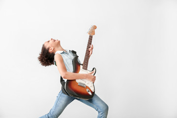 African-American girl playing guitar against light background