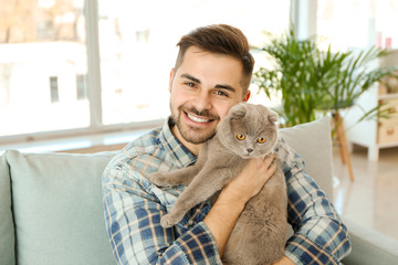Young man with cute funny cat at home