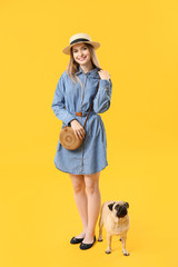Fototapeta premium Beautiful young woman with cute pug dog on color background