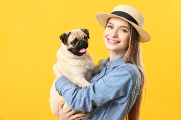 Beautiful young woman with cute pug dog on color background