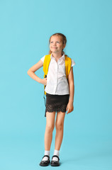 Cute little schoolgirl on color background