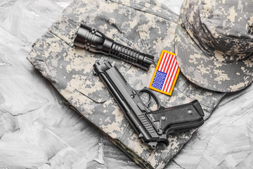 Military uniform, flashlight and gun on grey background