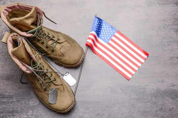 Military boots, USA flag and dog tag on grey background