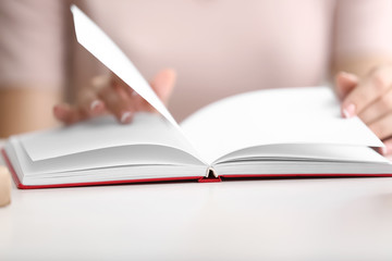 Woman reading book at table, closeup