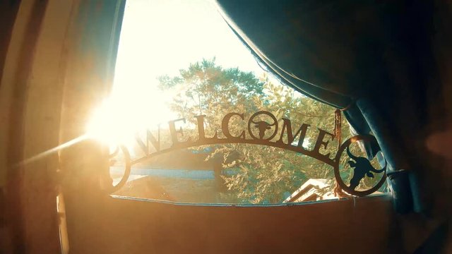 Welcome sign sitting in a screen door on the window frame on a sunny day. ( 4k footage )