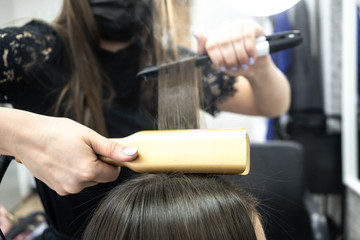 hairdresser makes hair lamination in a beauty salon for a girl with brunette hair