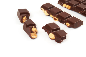 bar of dark chocolate with hazelnuts. Pieces of chocolate with nuts, isolated on white background.