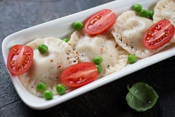 Vareniki or dumplings with green peas and cherry tomatoes, close-up, selective focus