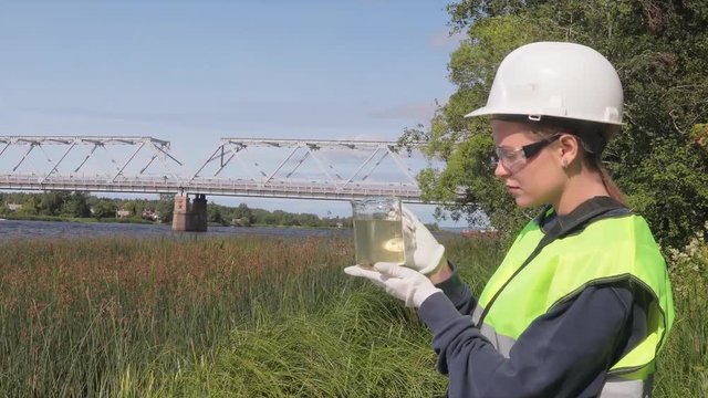 The ecologist carries out a visual express analysis of water in a reservoir and river. The data of the inspection of the coastal territory and the results of the analysis are recorded.