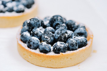 Delicious dessert blueberry mini tart with fresh berries and whipped cream. French cuisine. Berry pie with cream and icing sugar. Closeup. Shallow DOF