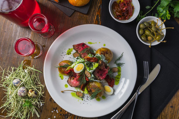 The red tincture and salad with roast beef and quail eggs on a wooden table