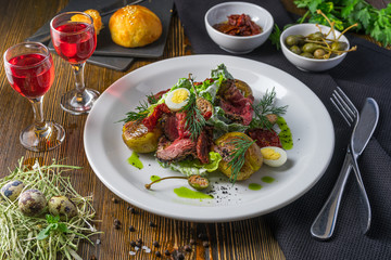 The red tincture and salad with roast beef and quail eggs on a wooden table
