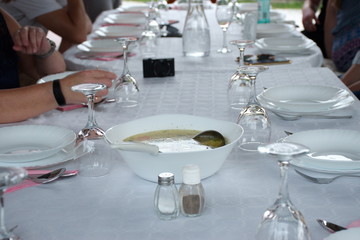 Table with white tablecloth preparing for dinner - soup in a white bowl