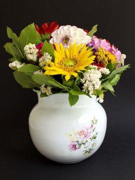 Colorful flowers in a vase against the black background