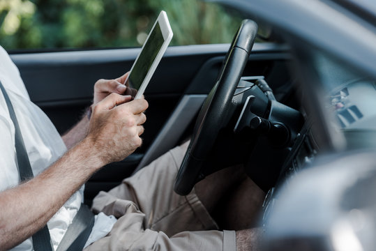 cropped view of man sitting in car and holding digital tablet