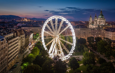 Budapest, Hungary - Aerial view of Elisabeth square at dusk with illuminated ferris wheel, St. Stephen's Basilica and Hungarian Parliament building at background. Summer evening in Budapest